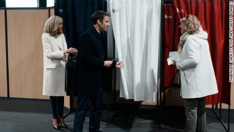 De Franse president Emmanuel Macron (midden), naast zijn vrouw Brigitte Macron (links), praat met een inwoner voordat hij gaat stemmen over de eerste ronde van de presidentsverkiezingen op zondag.