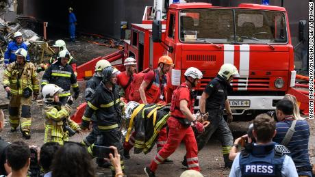 Reddingswerkers evacueren een persoon uit een flatgebouw dat op 26 juni 2022 is verwoest bij een Russische luchtaanval in het district Shevchenkivsky in Kiev.