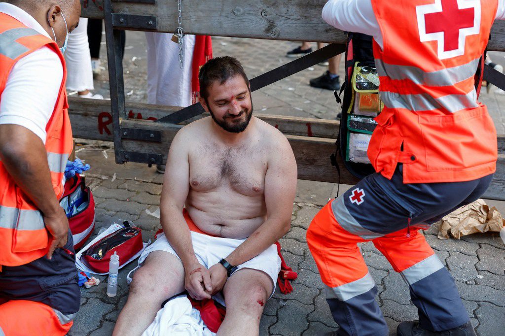 Een hardloper zonder shirt glimlacht ondanks het feit dat hij voor zijn verwondingen moet worden behandeld.