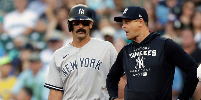 New York Yankees-coach Aaron Boone, tweede van rechts, en coach, rechts, praten met Matt Carpenter nadat hij een enkel schopte tegen de Seattle Mariners tijdens de eerste helft van een honkbalwedstrijd, maandag 8 augustus 2022, in Seattle.