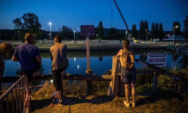 Omstanders en de lokale bevolking kijken naar een team van reddingswerkers terwijl ze een vermiste beluga-walvis vervoeren die vastzit in de Seine.