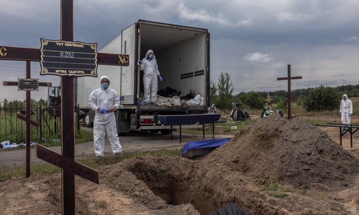 Arbeiders plaatsen de stoffelijke resten van de doden in de doodskisten van niet-geïdentificeerde mensen die zijn gedood in het district Bucha tijdens een massabegrafenis op een begraafplaats in Bucha, ten noordwesten van Kiev, Oekraïne.