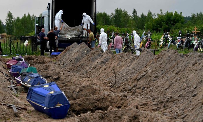 Gemeentewerkers verwijderen de lijkzakken van ongeveer een dozijn niet-geïdentificeerde burgers uit de achterkant van een mortuariumcontainer om ze in doodskisten te plaatsen die klaar zijn om te worden begraven op een plaatselijke begraafplaats in Bucha, in de regio van Kiev.
