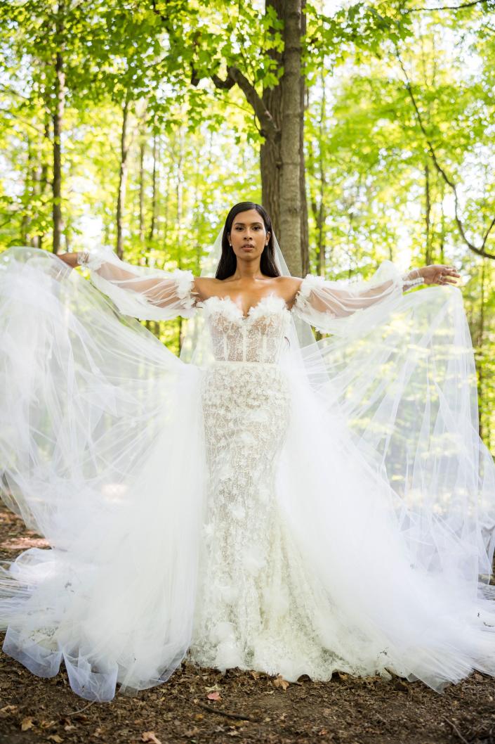 Een bruid die in haar trouwjurk in het bos staat.