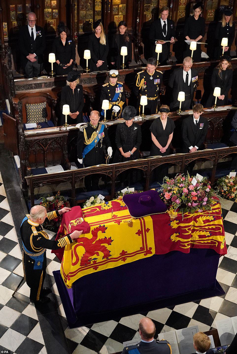 Koning Karel III legt de kleur van het kamp van de Queen's Company van de Grenadier Guards op de kist van Hare Majesteit tijdens de inbedrijfstellingsceremonie van maandag