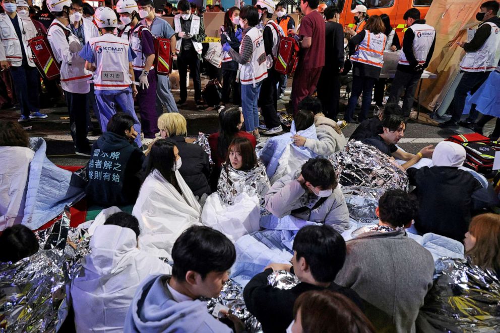 Foto: Mensen zitten op straat nadat ze zijn gered, op de plaats van tientallen gewonden bij een stormloop tijdens een Halloween-feest in Seoel, Zuid-Korea, 30 oktober 2022.