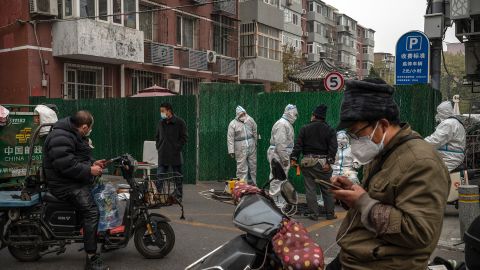 Covid-medewerkers in Hazmat-outfits helpen bezorgers bij het afleveren van goederen voor inwoners die op 24 november in Peking opgesloten zitten.