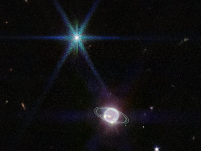 Een nabij-infrarood webcam (NIRCam) beeld van Neptunus en zijn ringen.  Neptunus heeft 14 bekende satellieten, en zeven daarvan zijn zichtbaar in deze afbeelding.