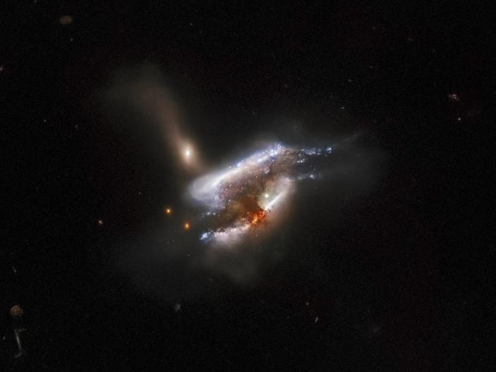 Drie met elkaar verweven sterrenstelsels versmelten in de zwarte ruimte
