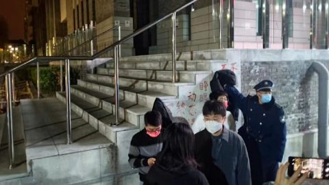 Een bewaker probeert een protestspandoek tegen Zero Covid te bedekken op de campus van de Universiteit van Peking in Peking.