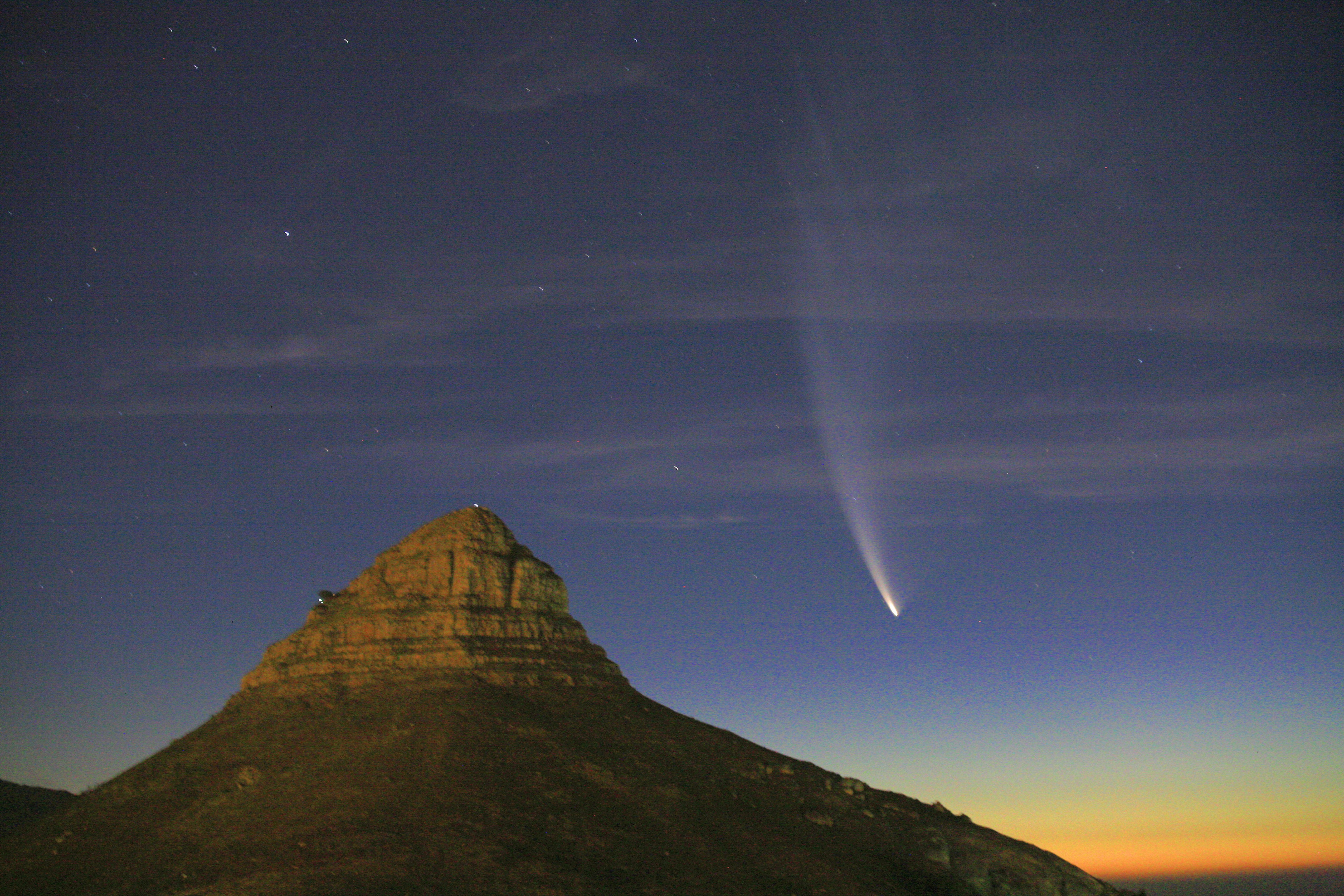 Een heldere komeet boven een berg bij zonsondergang