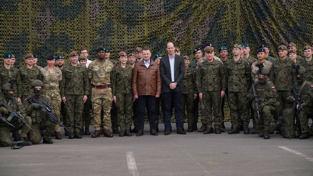Prins William en de Poolse vicepremier en minister van Defensie Mariusz Blaszczak (midden links) poseren voor een groepsfoto met Britse en Poolse troepen.