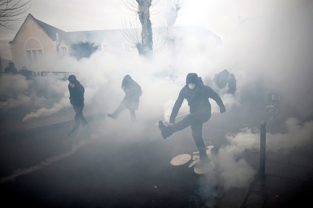 Gemaskerde demonstranten reageren te midden van traangasgranaten tijdens botsingen tijdens een demonstratie als onderdeel van de 11e dag van landelijke stakingen en protesten tegen de pensioenhervormingen van de Franse regering, in Rennes, Frankrijk, 6 april 2023.  