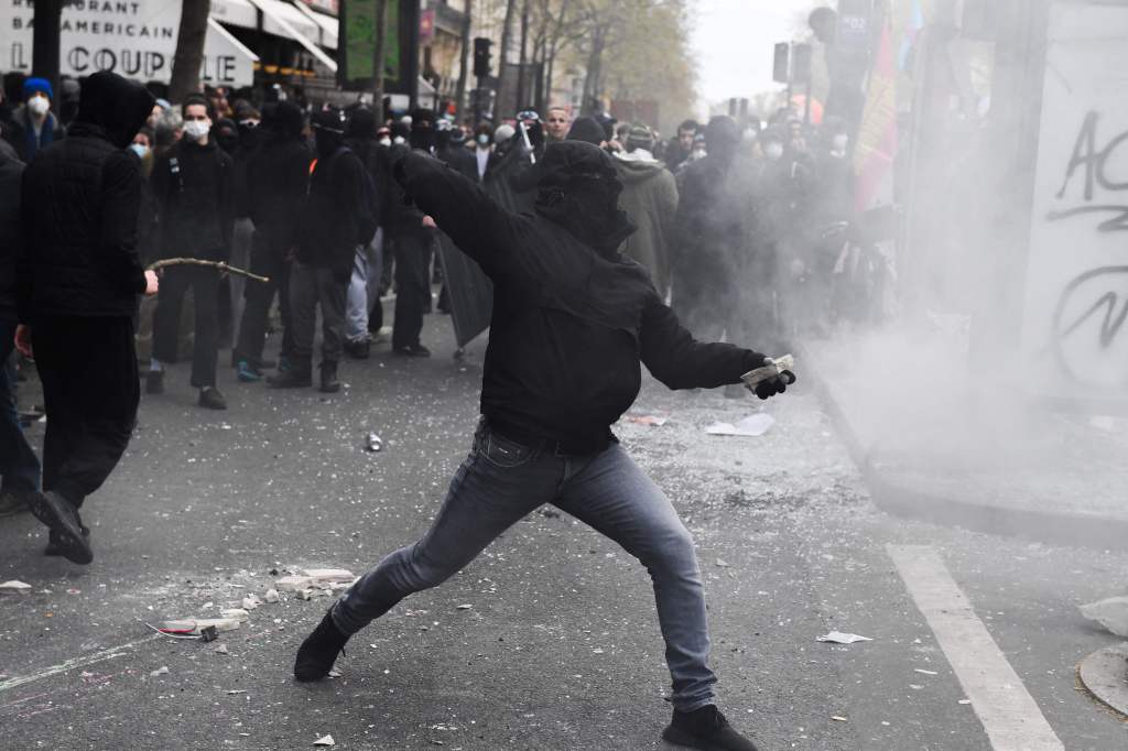 Een demonstrant gooit projectielen naar de oproerpolitie