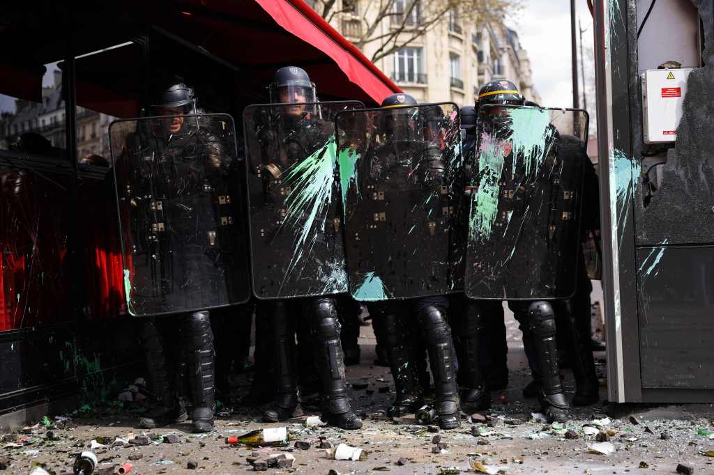 De Franse CRS-oproerpolitie beschermt zichzelf tegen projectielen en verf terwijl ze een cordon om hen heen vormen 