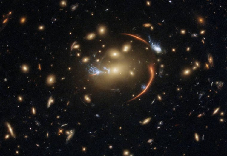 Afbeelding van veel sterrenstelsels, met enkele vervormde lijnen nabij het midden.