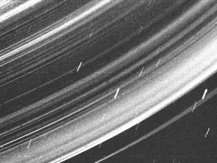 De korrelige zwart-witafbeelding toont een close-up van de ringen van Uranus.