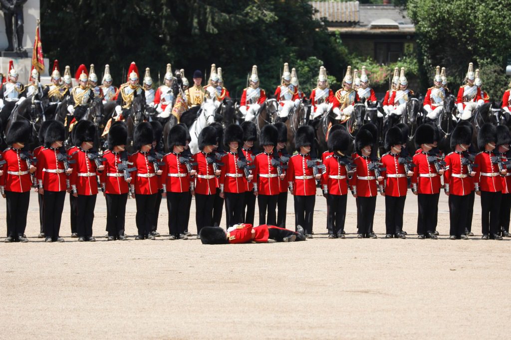 Britse bewakers staan ​​in formatie terwijl een van hen bewusteloos op de grond ligt.