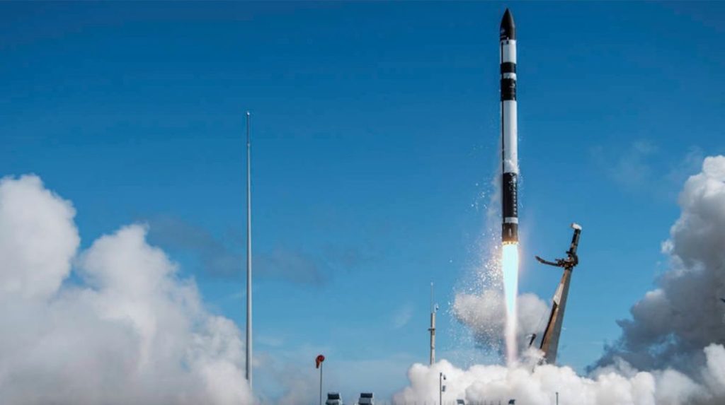 a black-and-white rocket lab electron rocket launches into a blue sky