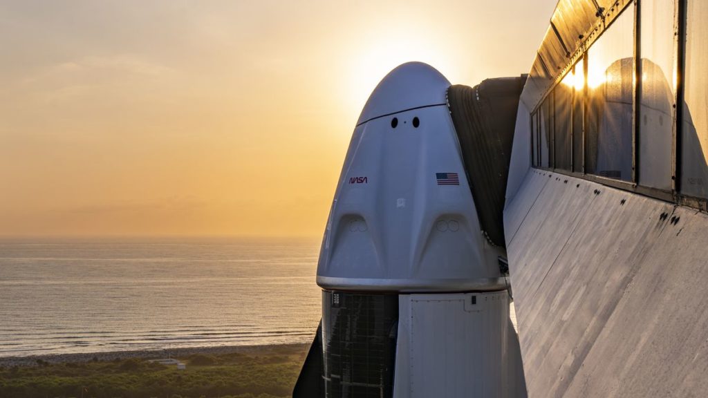 A white and black space capsule with fins as the sun rises behind it