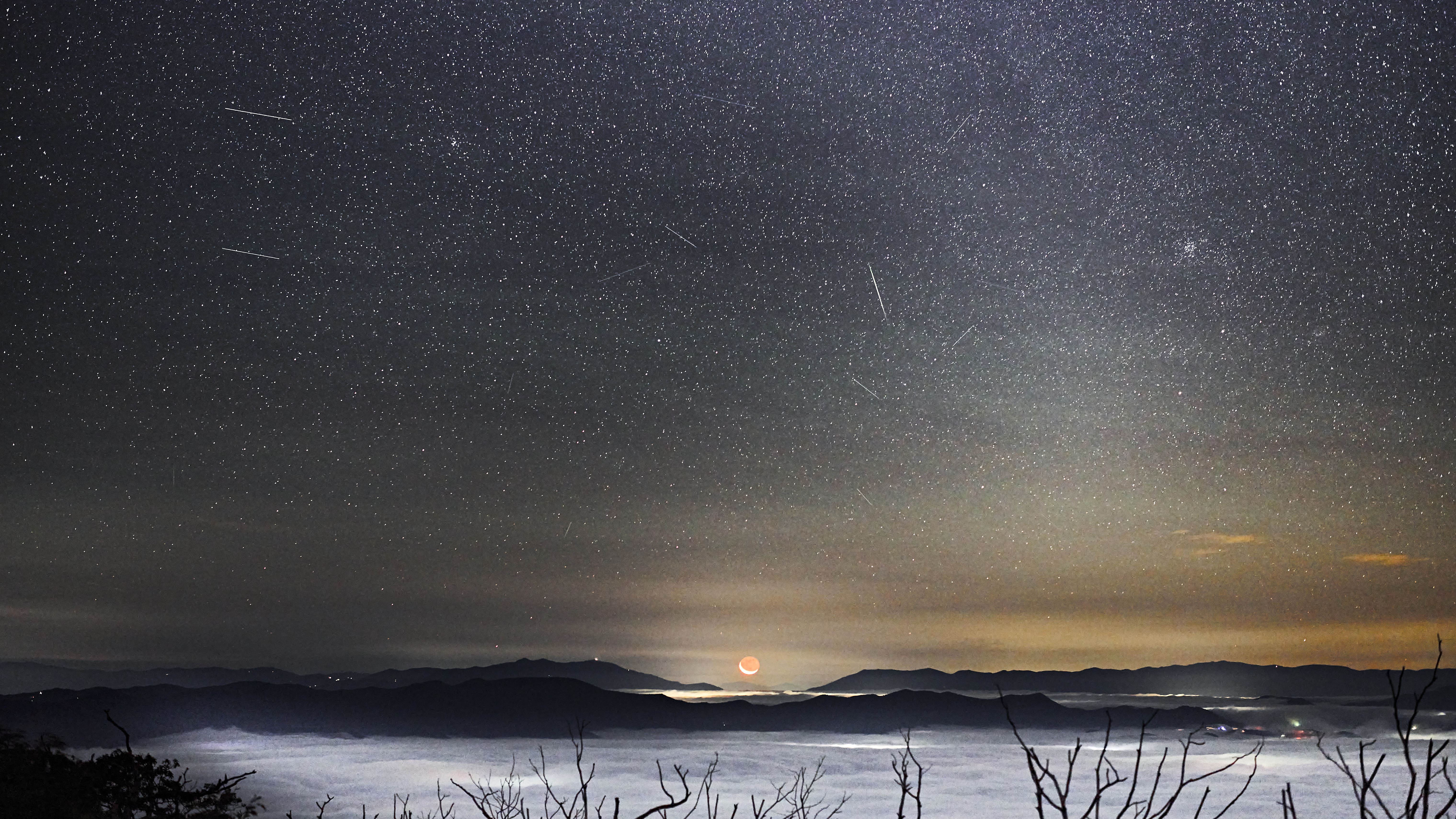 Een meteorenregen wordt afgebeeld tegen een sterrenhemel en een schilderachtige voorgrond