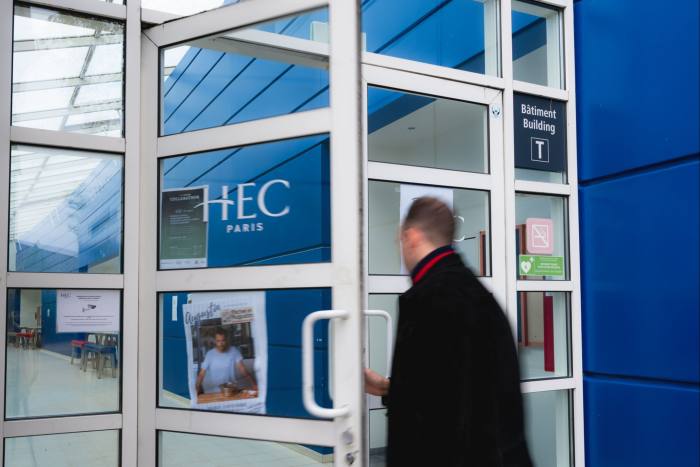 Een man loopt door een deur met een HEC Paris-bordje