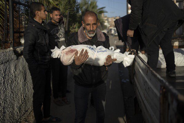 Een Palestijnse man draagt ​​het lichaam van zijn kleinzoon, die omkwam bij het Israëlische bombardement op de Gazastrook, in het Rafah-ziekenhuis, ten zuiden van Gaza, vrijdag 22 december 2023. (AP Photo/Fatima Shbair)