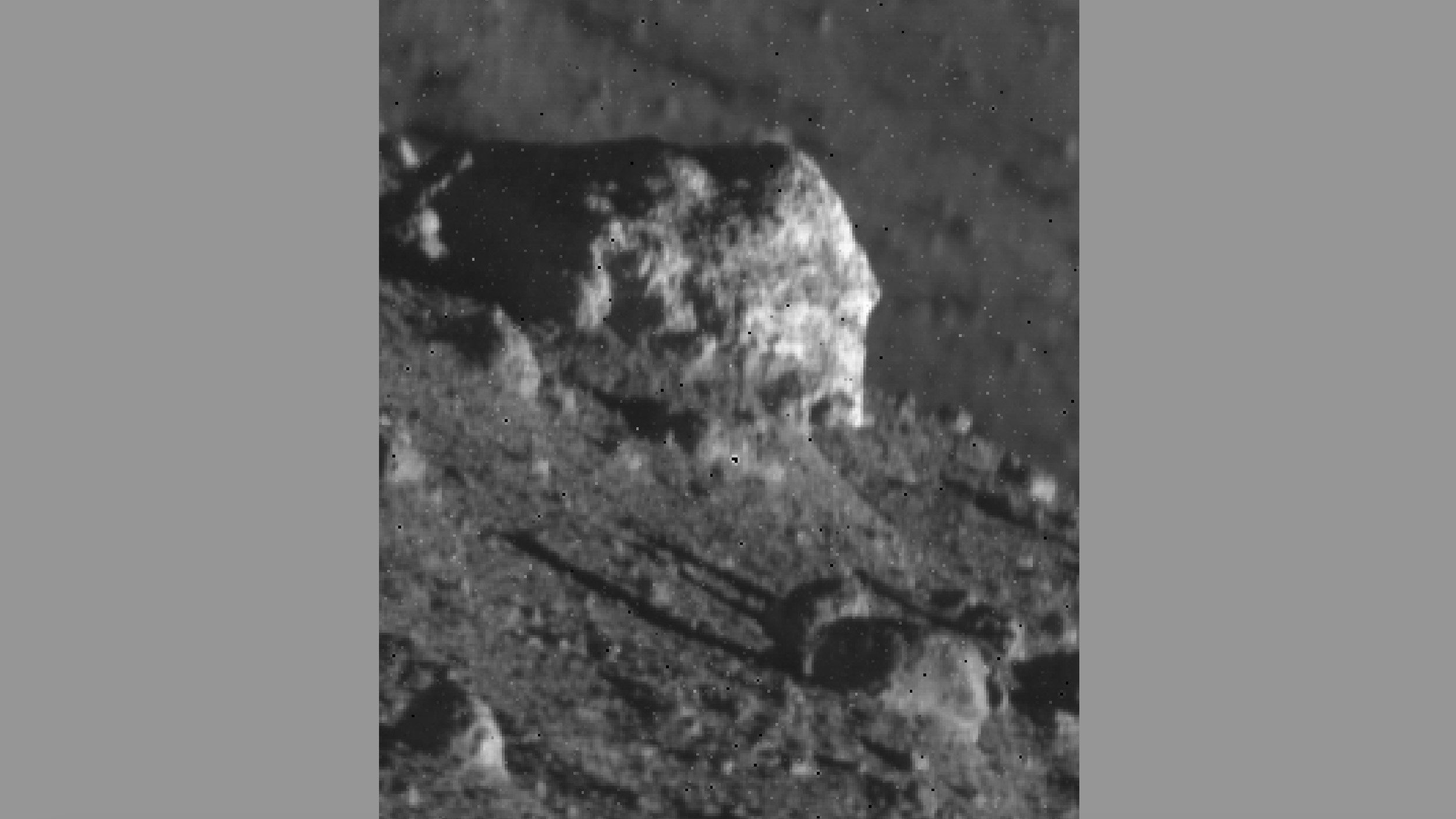 Een close-up van een grote rots op het maanoppervlak, omgeven door kleinere rotsen.