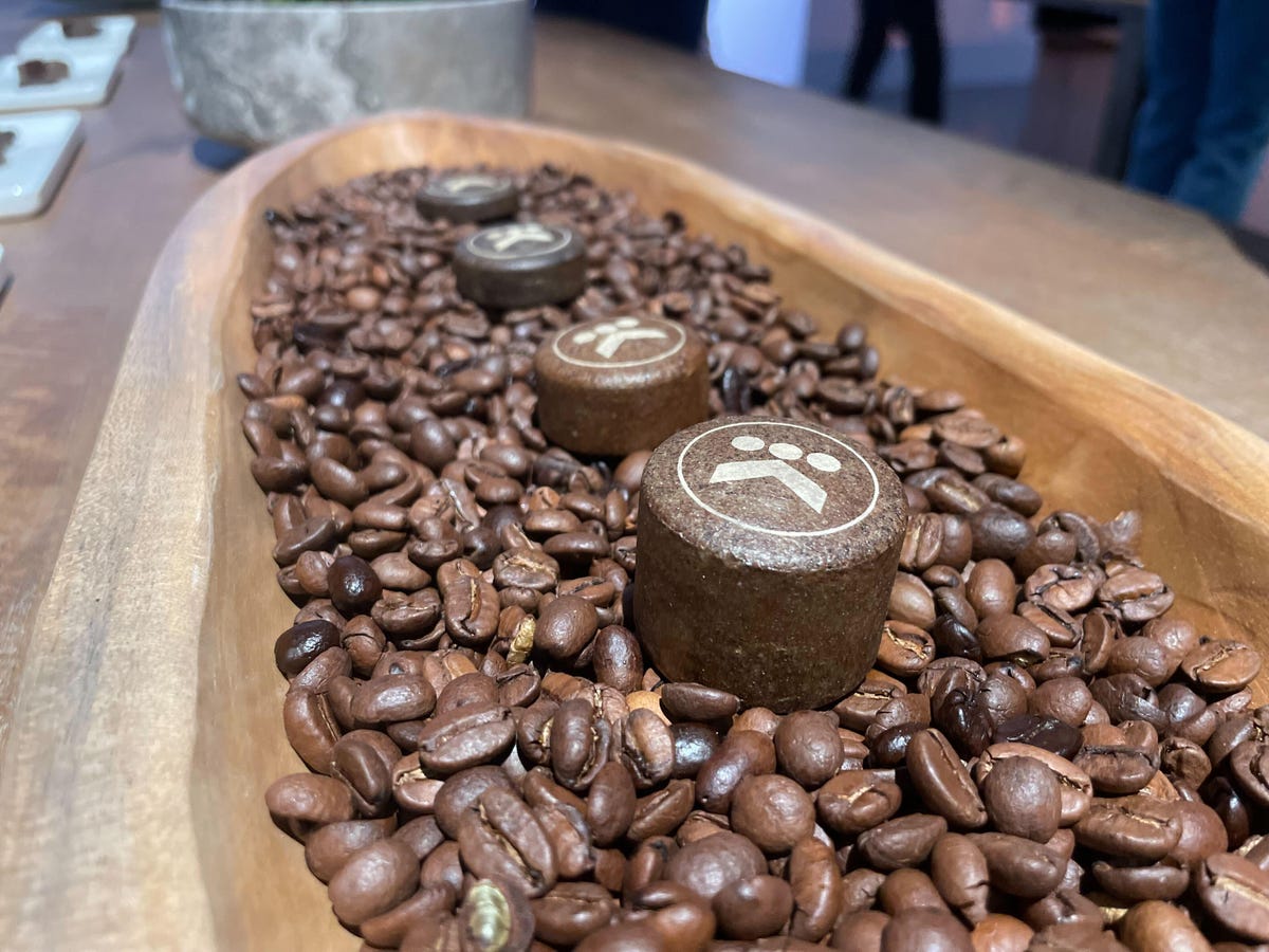 Een rij ronde, biologisch afbreekbare peulen in een laagje koffiebonen