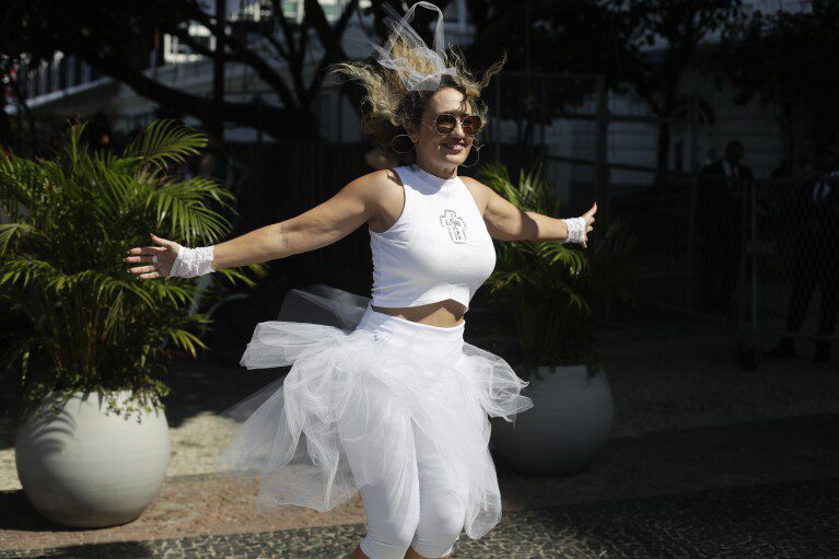 Een Madonna-fan danst buiten het Copacabana Palace Hotel waar Madonna verblijft voorafgaand aan haar concert in Rio de Janeiro, Brazilië, op vrijdag 3 mei 2024. Madonna sluit haar tour zaterdag af met een gratis concert op Copacabana Beach.  (AP-foto/Bruna Prado